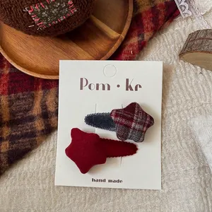 Detail of red and plaid star-shaped fabric hair clips on a white brand card display