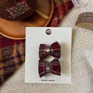 Detail view of red and grey plaid bow hair clips with gold metal charms on a card