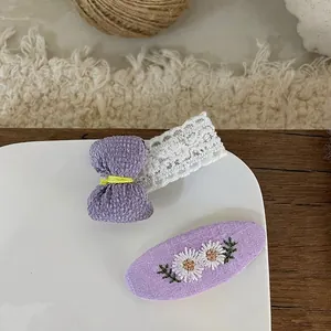 Close-up of handmade purple bow hairpins with lace and daisy embroidery details