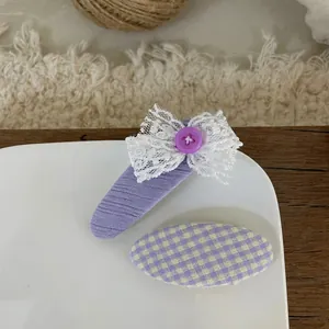 Detail of purple fabric hair clips with lace bow and plaid pattern on ceramic plate
