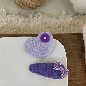 Close-up of handmade purple fabric hair clips with heart and houndstooth bow details