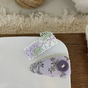 Detail of handmade lace and floral fabric hair clips in soft purple and white colors