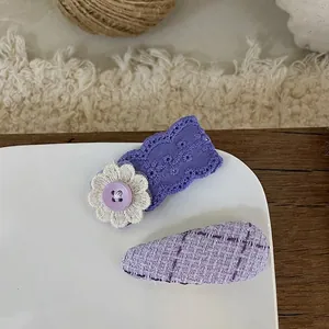 Detail of purple lace and tweed fabric hair clips with button and floral embroidery