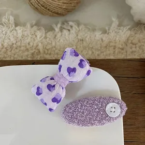Detailed shot of purple fabric bow hair clips with heart patterns and button accents