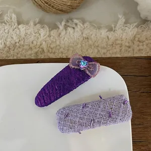 Detailed close-up of handmade purple fabric bow hair clips with sequins and heart gems