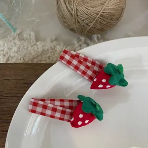 Détail de barrettes fraises avec tissu à carreaux rouges et finitions brodées