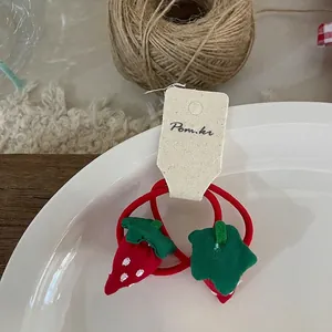 Détails des chouchous fraises rouges élastiques avec feuilles vertes sur une assiette