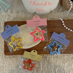 Barrettes à cheveux en forme d'étoile jaune, rose, bleu et orange sur plateau en bois
