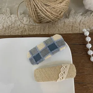 Detail of blue checkered fabric and lace floral hair clips on a white porcelain tray
