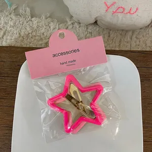Gros plan sur une pince à cheveux étoile rose avec base en métal doré sur assiette blanche