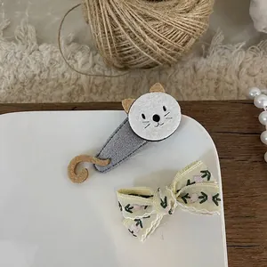 Close-up of cat felt clip and floral bow hairpin on elegant white ceramic plate