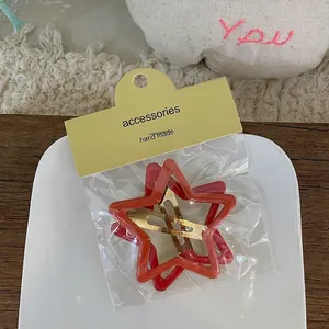 Détail de barrettes en forme d'étoile rouge et orange avec une finition laquée brillante