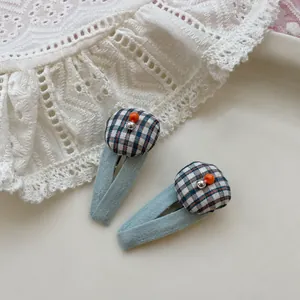 Gros plan de deux pinces à cheveux à carreaux bleu clair sur de la dentelle blanche