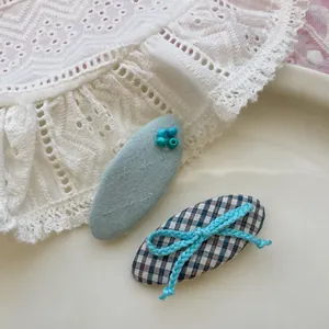 Détail de barrettes à carreaux bleus avec nœud et pinces brodées de perles sur un plateau