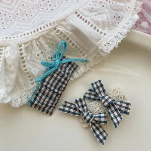 Détails de barrettes à carreaux avec dentelle délicate et nœud en tissu bleu doux