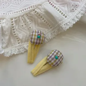 Détail de deux pinces BB en tissu jaune avec coussinets à carreaux et perles bleues