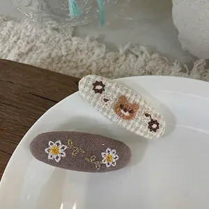 Nahaufnahme handbestickter Haarspangen aus Stoff mit Bären- und Gänseblümchen-Mustern