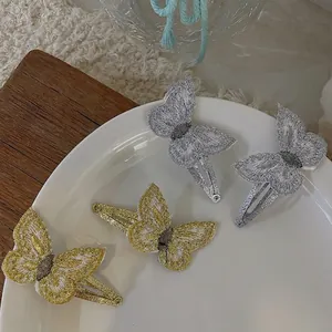 Glittery gold and silver embroidered butterfly hair clips for girls set on white tray