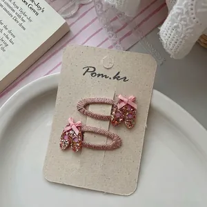 Detail of pink ballet shoe hair clips with glitter coating and silk bows on card