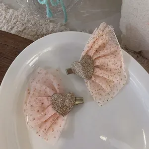 Detail view of pink mesh star wing hair clips with golden heart center on a white plate