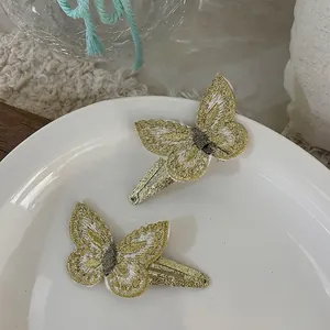 Detailed close-up of embroidered butterfly hair clips with gold sequins and soft white mesh