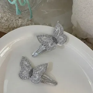 Detailed view of silver sequin butterfly hair clips on a white ceramic plate