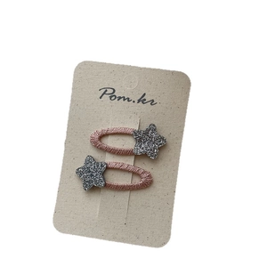 Pair of sparkling star hair clips with glitter finish on textured pink gold base