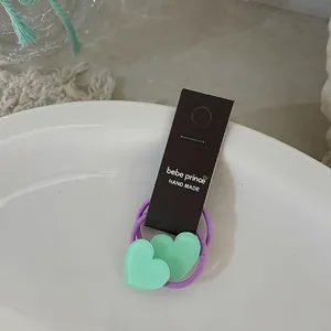 Détail de chouchous cœur vert menthe avec élastique violet sur une carte de support