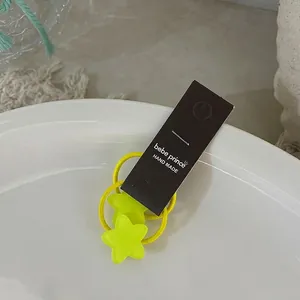 Détail d'élastiques étoiles jaune vif sur carton noir pour coiffures d'enfants