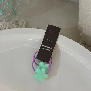 Gros plan d'élastiques à cheveux violets avec breloques fleurs vert menthe sur carte
