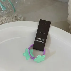 Détail de l'élastique à cheveux violet avec breloques étoiles vert menthe sur céramique