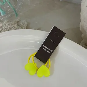 Détail de chouchous en forme de cœur jaune fluo sur une assiette blanche avec carte