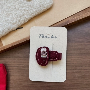 Handmade dark red fabric hair clip with beige lace and a purple button on a display card