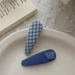 Dettaglio di fermagli in tessuto blu a quadretti e volant su un piatto bianco