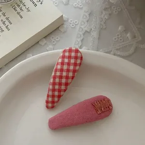 Dettaglio di fermagli in tessuto a quadretti rossi e rosa su piatto in ceramica