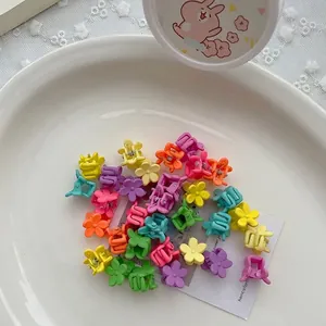 Detailopname van kleurrijke macaron mini bloem haarspeldjes voor meisjes op wit bord