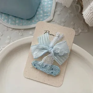 Gros plan détaillé de pinces à cheveux en dentelle bleu clair et ruban texturé sur carte