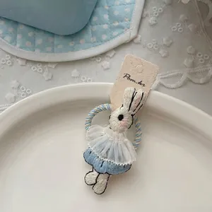 Détail d'un élastique à cheveux lapin brodé avec robe bleue et bordure en dentelle
