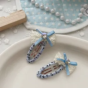 Dettaglio di fermagli per capelli blu a pois con fiocchi di pizzo su un piatto bianco
