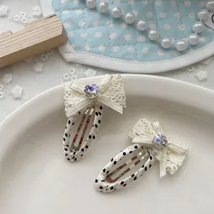 Dettaglio delle mollette a pois con fiocchi di pizzo e strass cangianti