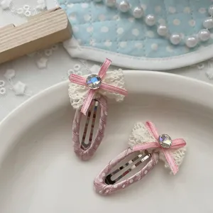 Dettaglio di fermagli rosa a pois con fiocchi in pizzo crema e strass luccicanti