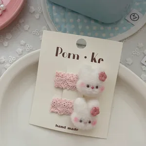 Detalle de horquillas de conejo de peluche con encaje rosa y bordado infantil