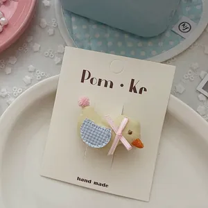 Detalle de accesorio para pelo de pollito hecho a mano con alas de cuadros azules