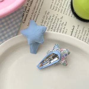 Détail de pinces à cheveux étoiles en tissu floral et bleu avec clips BB en métal