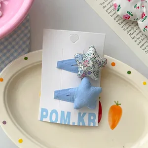 Détail de barrettes en tissu étoile à fleurs et bleues sur une carte de présentation