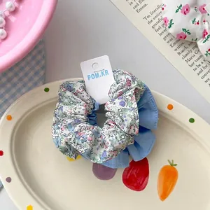 Gros plan d'un chouchou en tissu floral avec coutures bleues sur une assiette décorative