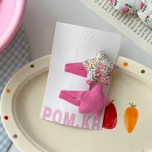 Détail de pinces à cheveux en étoile en tissu floral et rose sur carte blanche