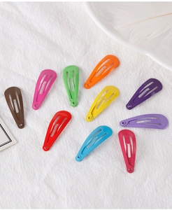 Détail de dix barrettes goutte de 3cm en métal coloré sur une texture blanche