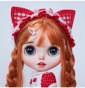Close-up of a Blythe style doll featuring orange braided hair and red strawberry lace outfit