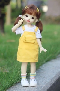 Detail of high-quality BJD doll wearing a yellow pinafore dress and white cotton t-shirt